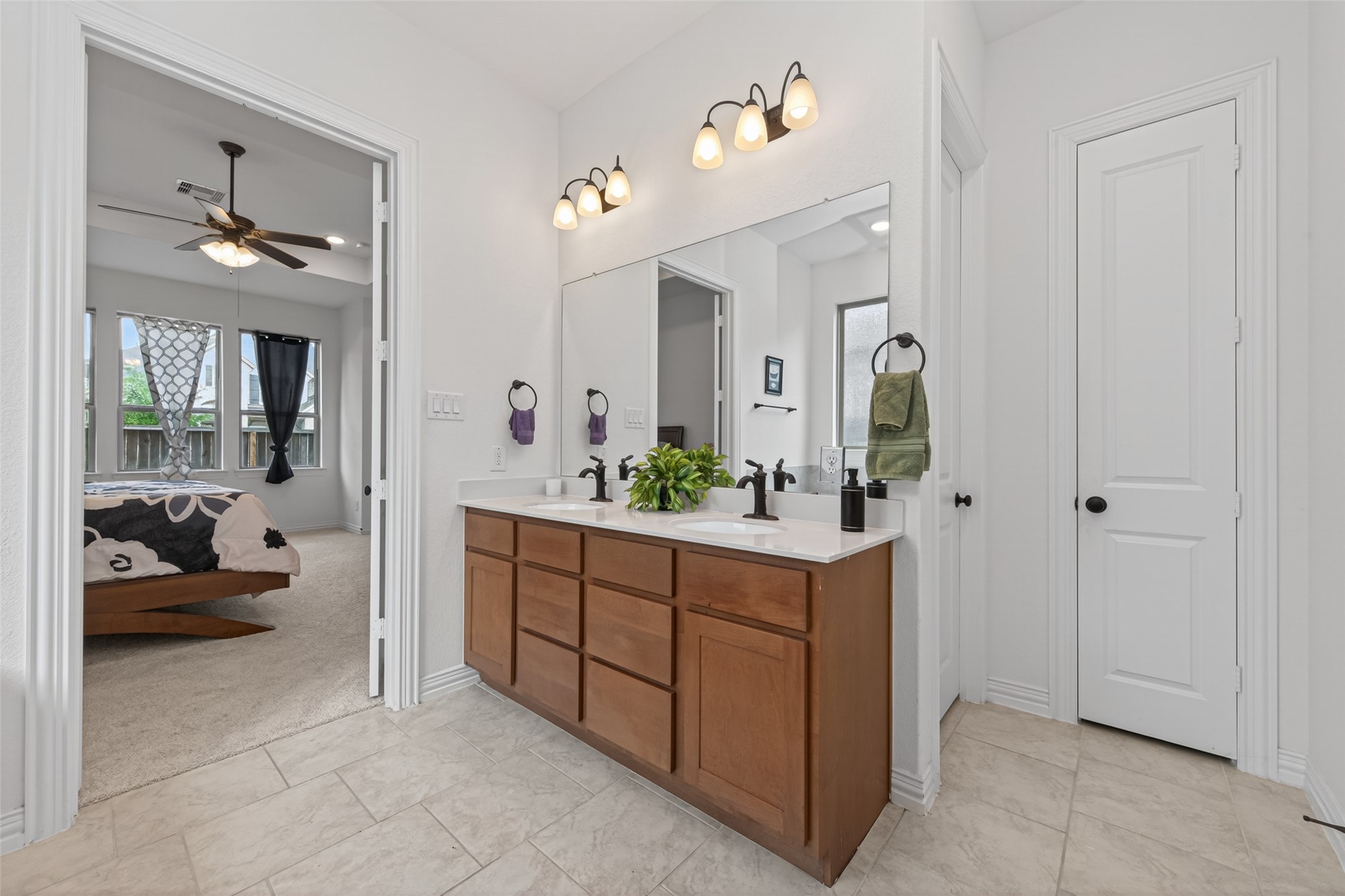 20802 Mirror Point Drive Cypress, TX 77433 - Photo 28 of 37 Step into this luminous and inviting bathroom, featuring dual sinks and stylish, modern light fixtures for a spa-like ambiance. A practical closet and ample storage under the sinks provide organized space for all essentials, resulting in a functional and aesthetically pleasing space.