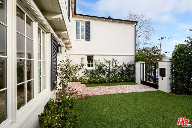 a view of a house with brick walls and a yard with potted plants