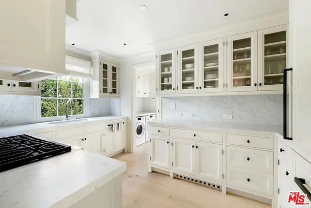 a kitchen with granite countertop a stove a sink and white cabinets with wooden floor