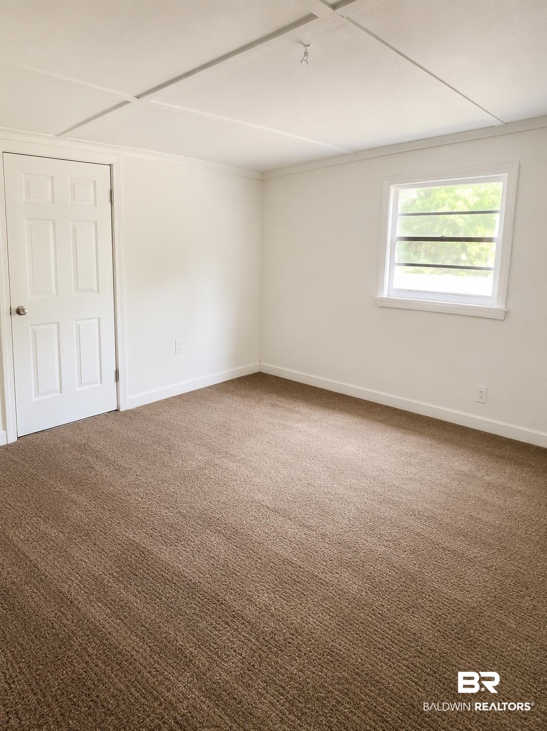 226 Elizabeth Street Evergreen, AL 36401 - Photo 32 of 35 Bright interior room featuring neutral-toned carpet, white walls, white trim, and a paneled white door