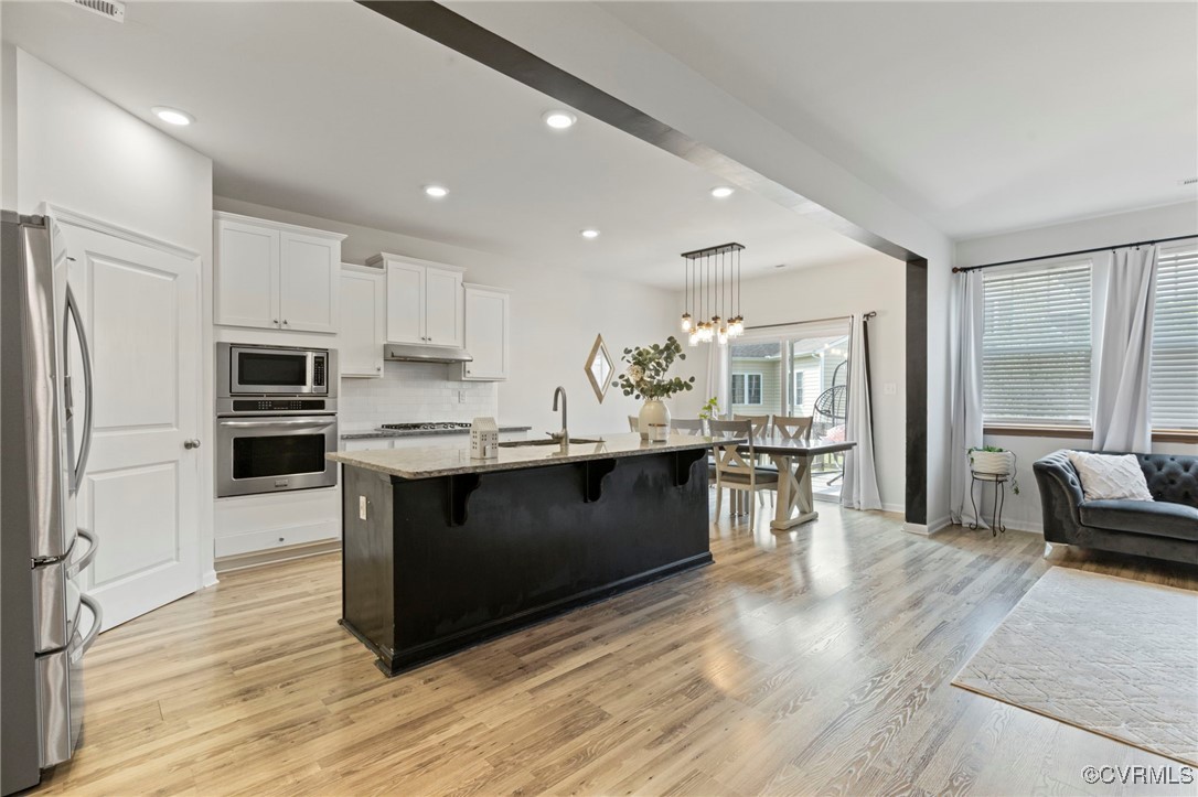 9801 Cravensford Loop Midlothian, VA 23112 - Photo 22 of 49 a kitchen with stainless steel appliances kitchen island granite countertop a stove top oven a sink dishwasher a refrigerator and a dining table with wooden floor