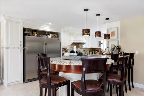 a dining room with stainless steel appliances kitchen island granite countertop a table chairs and a refrigerator