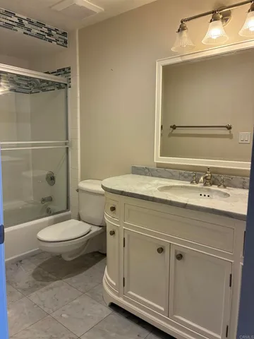 a bathroom with a granite countertop toilet sink and mirror