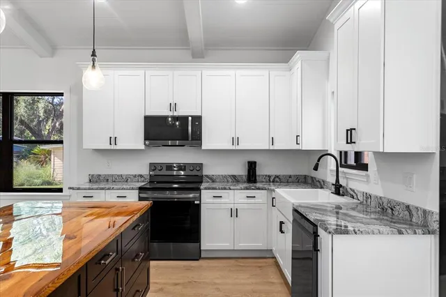 a kitchen with stainless steel appliances granite countertop a sink stove oven and white cabinets