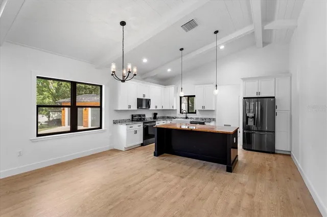 a large kitchen with kitchen island a stove a refrigerator a sink dishwasher and a fireplace with wooden floor