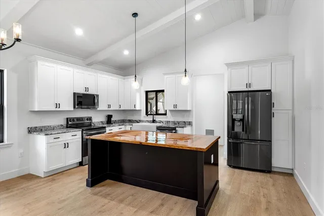 a kitchen with stainless steel appliances granite countertop a refrigerator a sink dishwasher a stove and white cabinets with wooden floor