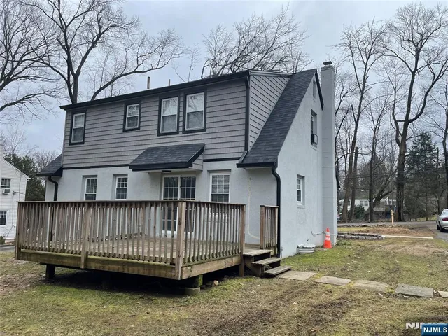 a view of a house with a wooden deck and a forest