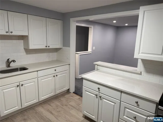 a kitchen with white cabinets and sink