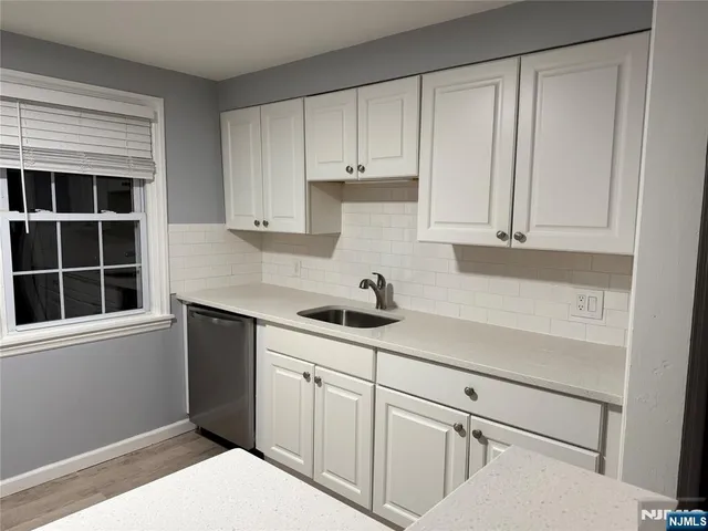 a kitchen with white cabinets and window