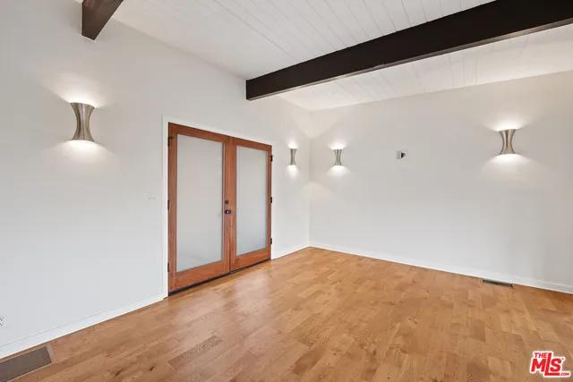 a view of a hallway with wooden floor and a bathroom