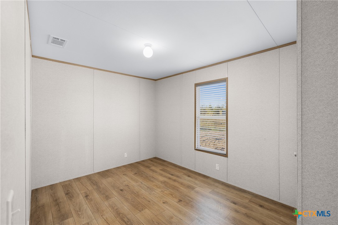 139 Azalea Ct Dale Dale, TX 78616 - Photo 18 of 26 a view of an empty room with wooden floor and a window