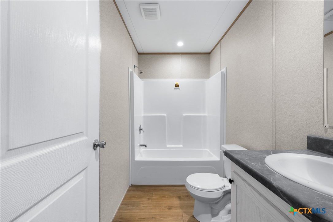 139 Azalea Ct Dale Dale, TX 78616 - Photo 20 of 26 a bathroom with a granite countertop toilet a sink and a mirror