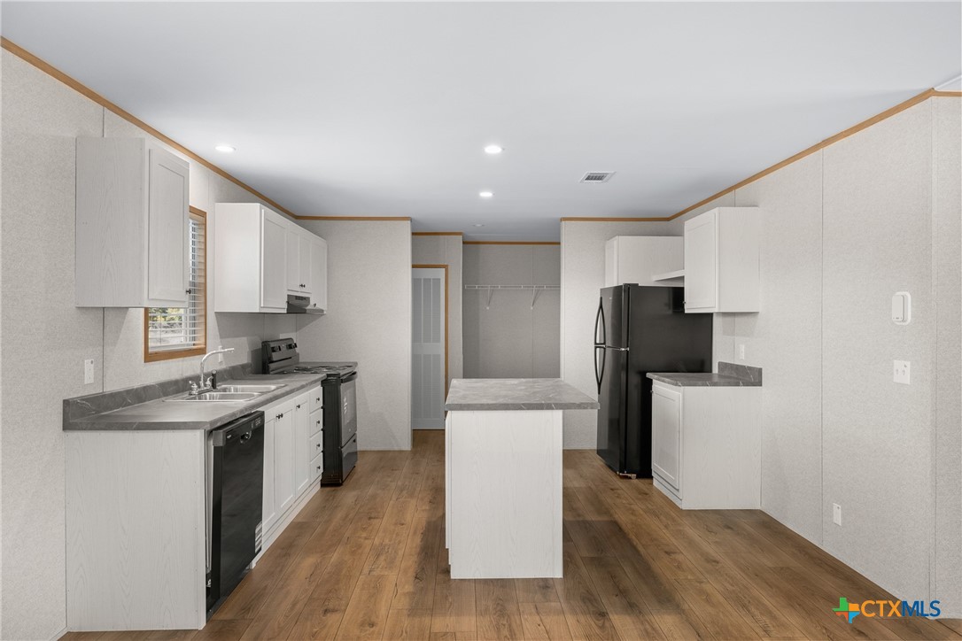 139 Azalea Ct Dale Dale, TX 78616 - Photo 8 of 26 a kitchen with stainless steel appliances a stove a sink a refrigerator white cabinets and wooden floor