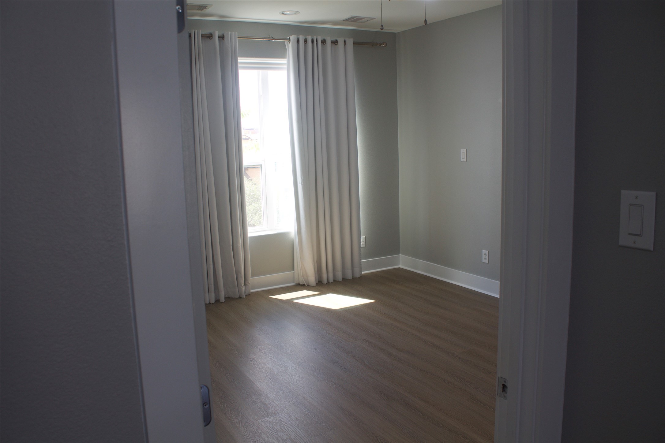 3105 Gillespie Street Houston, TX 77020 - Photo 30 of 43 an empty room with wooden floor and windows with curtains