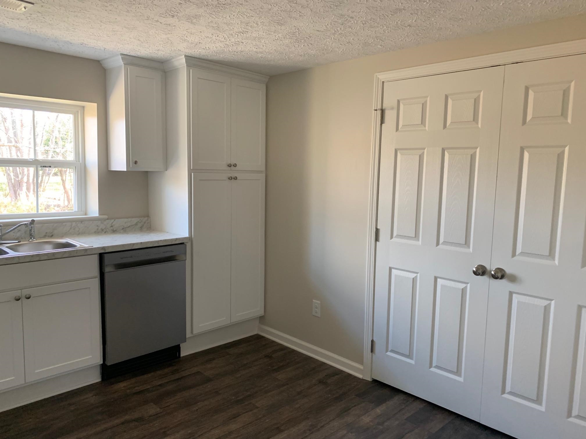 1612 Old Brownsville Road Ripley, TN 38063 - Photo 11 of 13 Kitchen with dark hardwood / wood-style flooring, stainless steel dishwasher, a textured ceiling, sink, and white cabinets