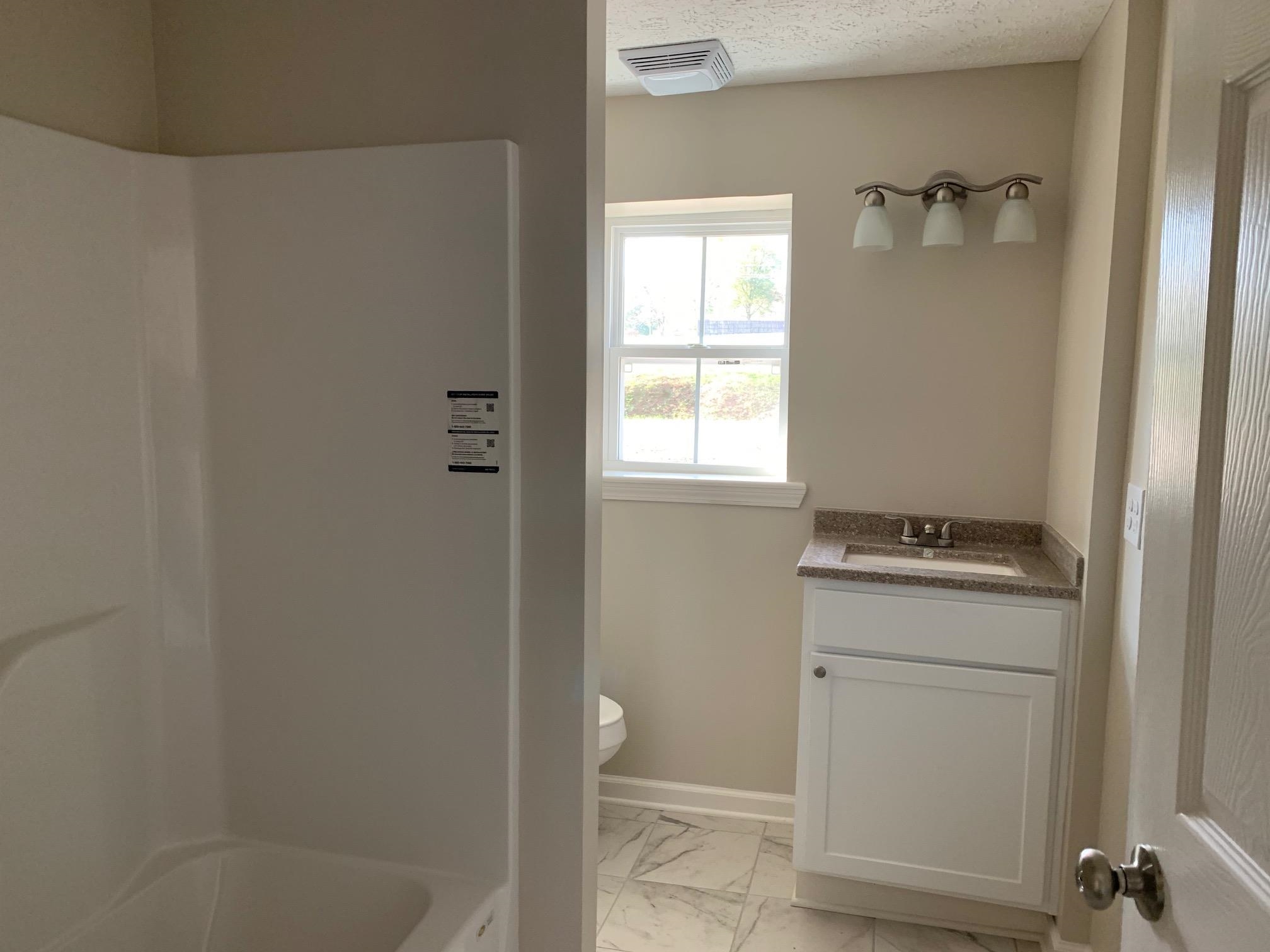 1612 Old Brownsville Road Ripley, TN 38063 - Photo 9 of 13 Bathroom with vanity, toilet, and a textured ceiling