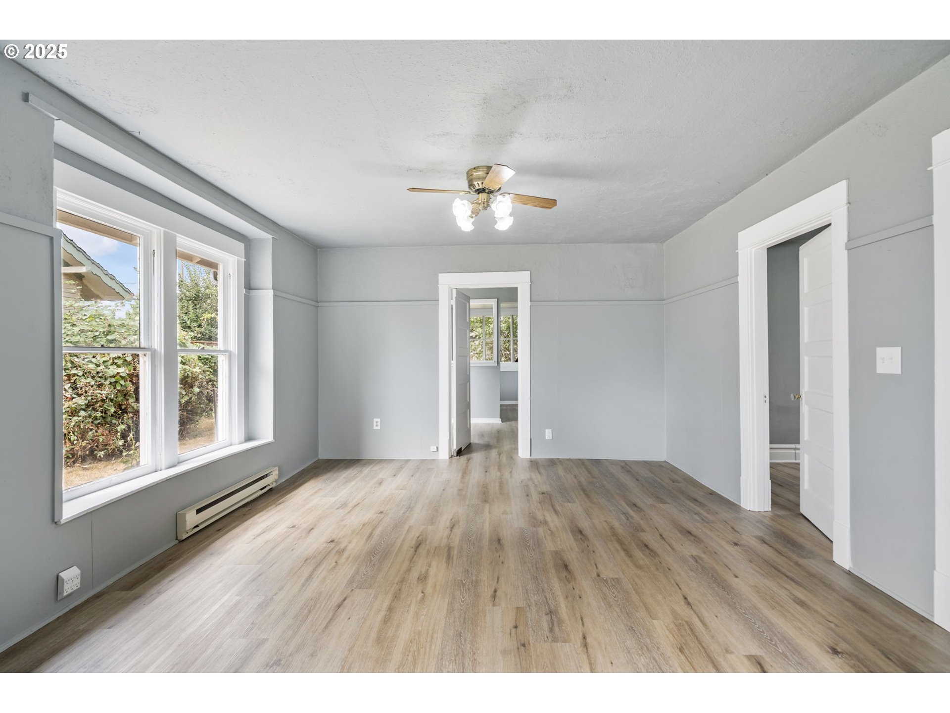 2035 4th Street Northeast Salem, OR 97301 - Photo 9 of 45 an empty room with wooden floor chandelier fan and windows