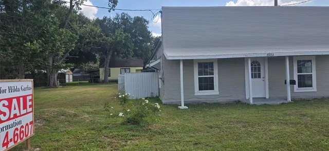 a backyard of a house with plants and large tree