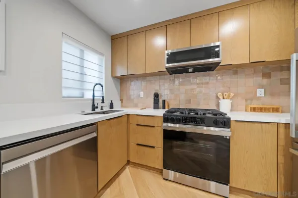 a kitchen with stainless steel appliances granite countertop white cabinets a stove top oven a sink and dishwasher