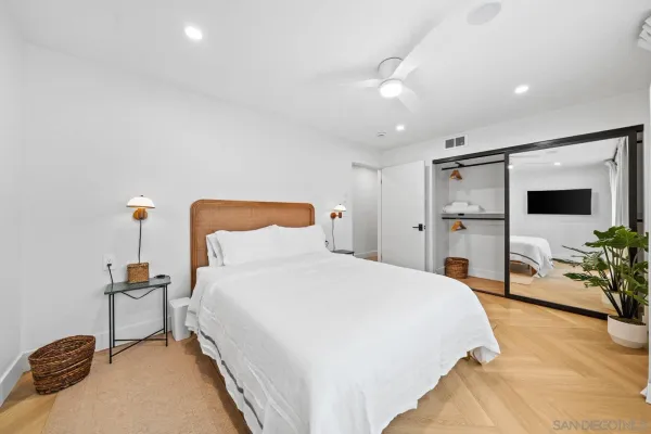 a spacious bedroom with a bed and a flat tv screen on dresser