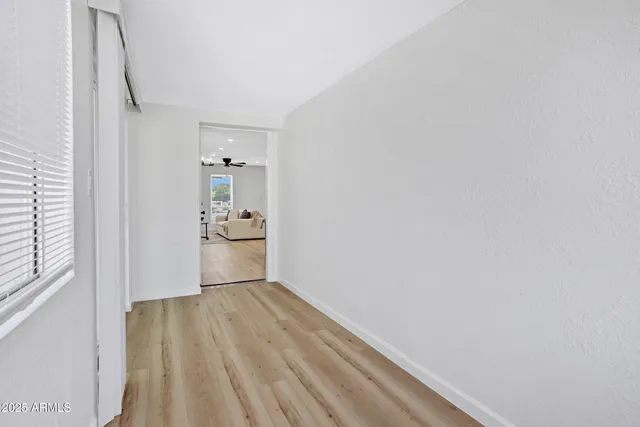 a view of empty room with wooden floor and fan