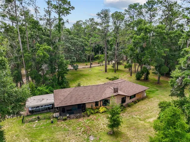 an aerial view of a house with swimming pool and a yard