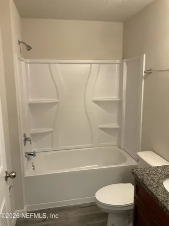 a bathroom with a granite countertop toilet and a tub