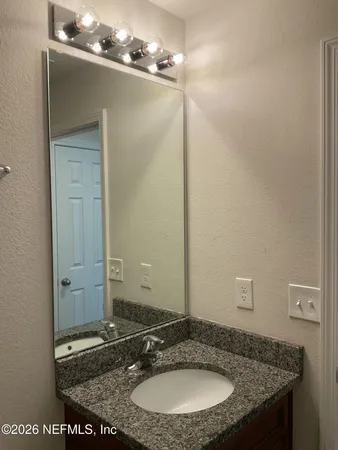 a bathroom with a granite countertop sink and a mirror