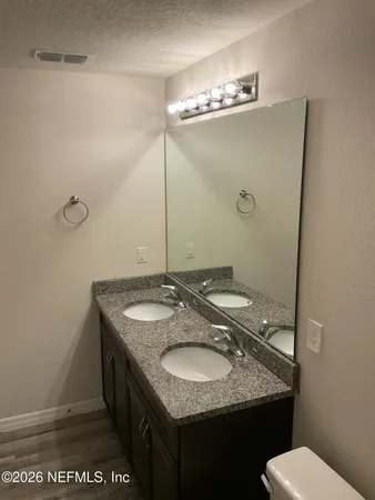 a bathroom with a granite countertop sink a toilet and a mirror