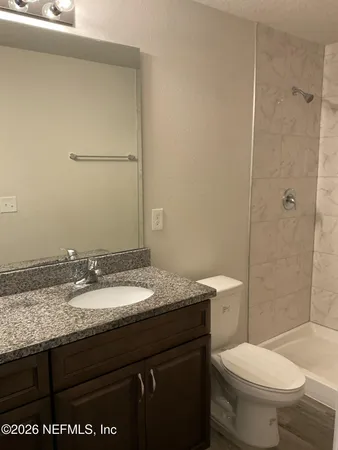a bathroom with a granite countertop sink toilet and a mirror