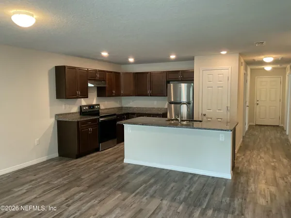 a kitchen with stainless steel appliances granite countertop a stove a sink and a refrigerator