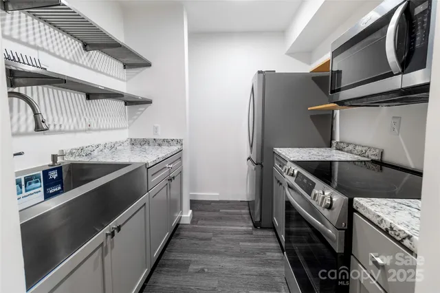 a kitchen with stainless steel appliances granite countertop a stove a sink and a refrigerator