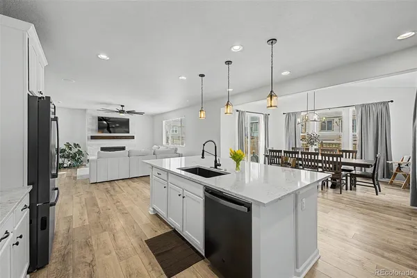 a open kitchen with stainless steel appliances granite countertop a sink dishwasher a refrigerator and a dining table with wooden floor