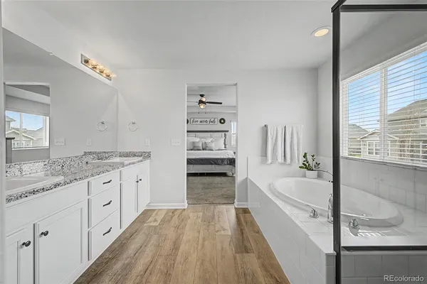 a bathroom with a granite countertop tub a sink and a large window