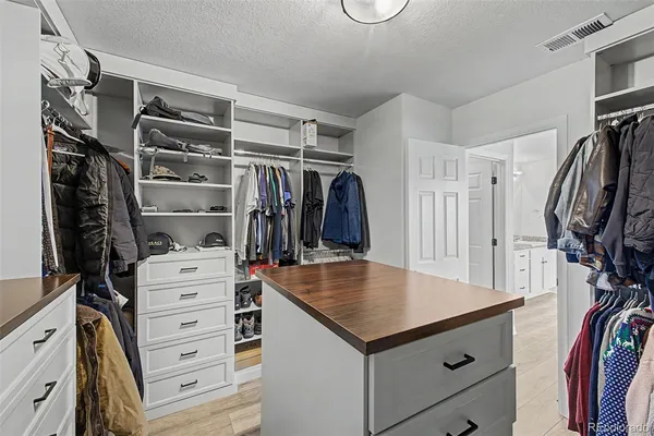 a view of walk in closet with clothes and shoes