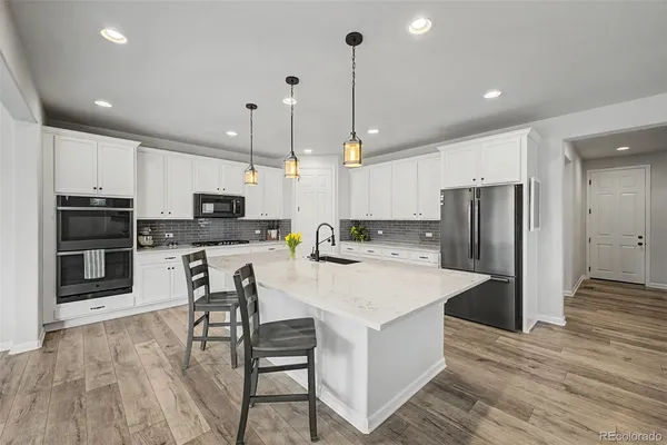 a kitchen with stainless steel appliances kitchen island granite countertop a refrigerator a stove top oven a sink and chairs