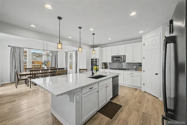 a kitchen with stainless steel appliances granite countertop a refrigerator a oven and white cabinets with wooden floor