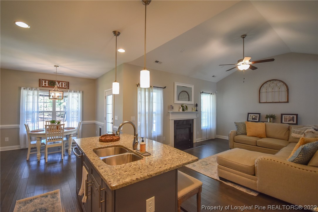 515 Bristling Pine Road Carthage, NC 28327 - Photo 20 of 40 a living room with furniture a rug kitchen view and a chandelier