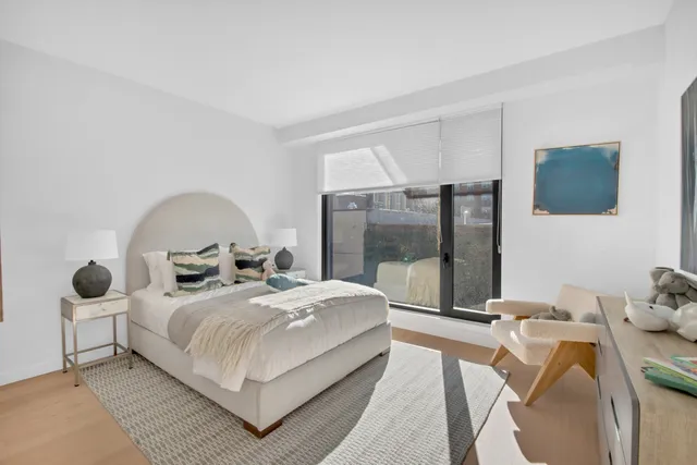 a bedroom with a bed a lamp and a large window