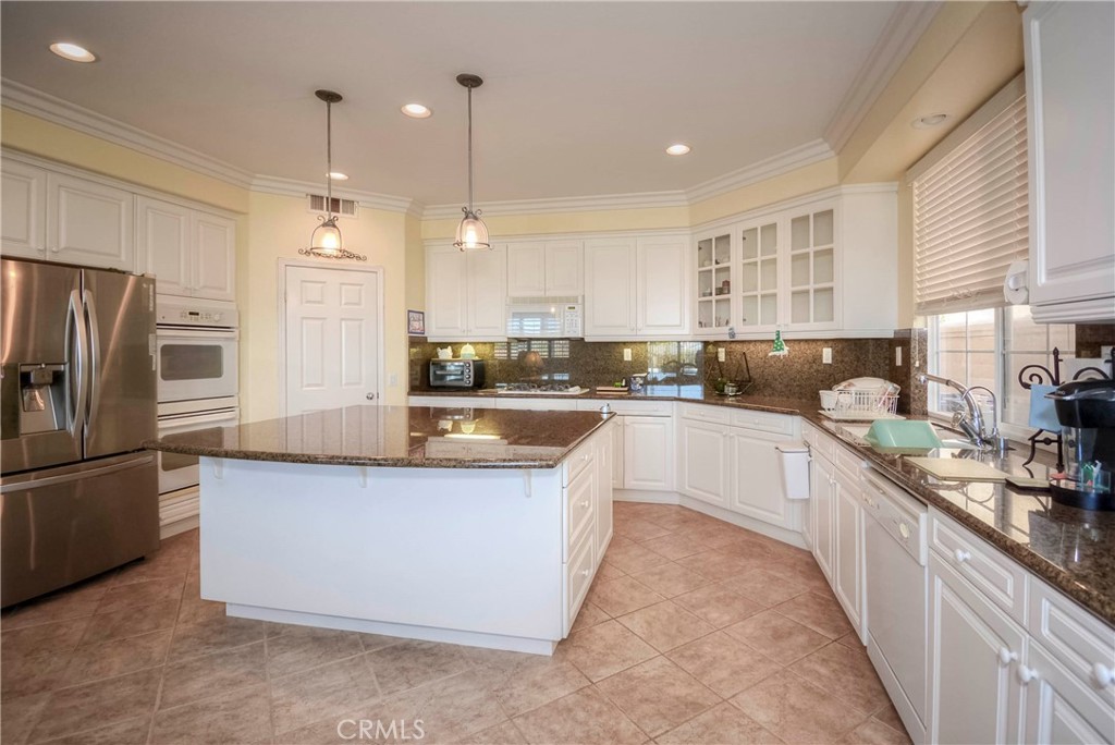 45316 St Tisbury Street Temecula, CA 92592 - Photo 11 of 62 a large kitchen with stainless steel appliances kitchen island granite countertop a refrigerator a sink a stove and oven