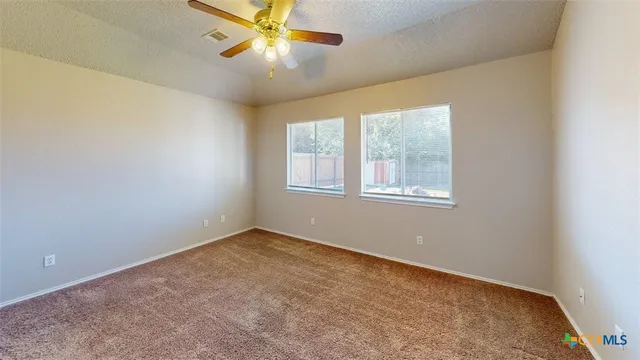 an empty room with windows and fan