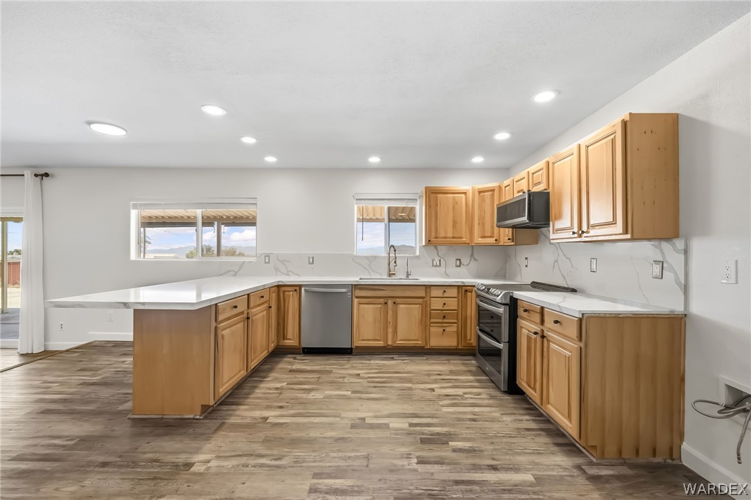 4088 Mercer Road Bullhead City, AZ 86429 - Photo 11 of 35 Spacious kitchen featuring light wood cabinetry, stone-look countertops, and a coordinating stone-look backsplash