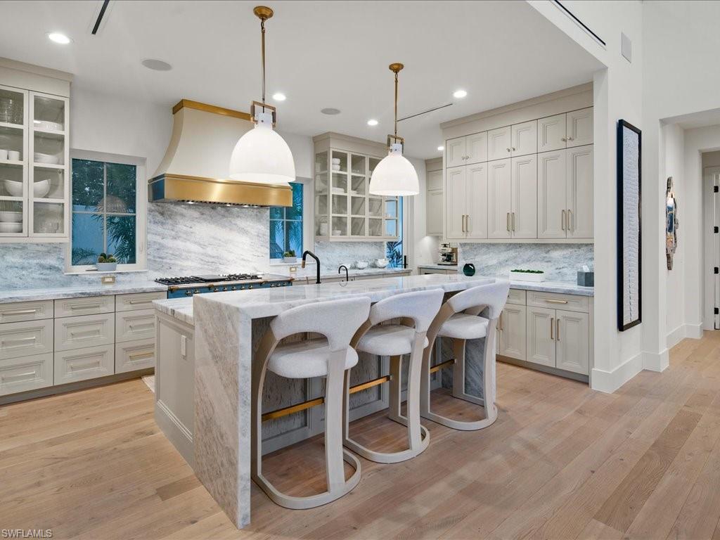 9185 Mercato Way Naples, FL 34108 - Photo 20 of 50 a kitchen with granite countertop a sink stove a refrigerator and a dining table with wooden floor