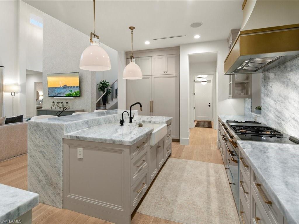 9185 Mercato Way Naples, FL 34108 - Photo 24 of 50 a large kitchen with kitchen island a stove a sink a refrigerator and a dining table with wooden floor