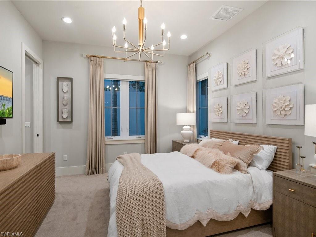 9185 Mercato Way Naples, FL 34108 - Photo 30 of 50 a bedroom with a large bed and a chandelier