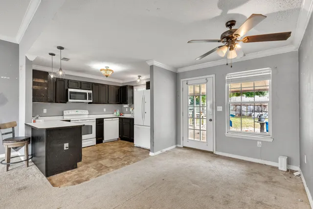 a large white kitchen with a refrigerator a stove top oven and a sink