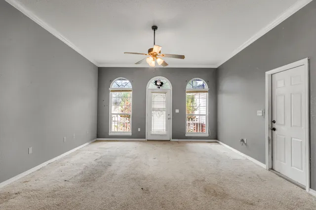 an empty room with windows and fan