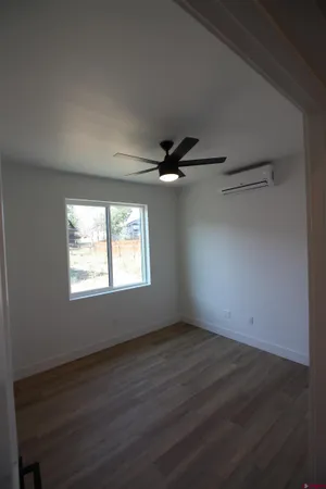 an empty room with wooden floor fan and windows