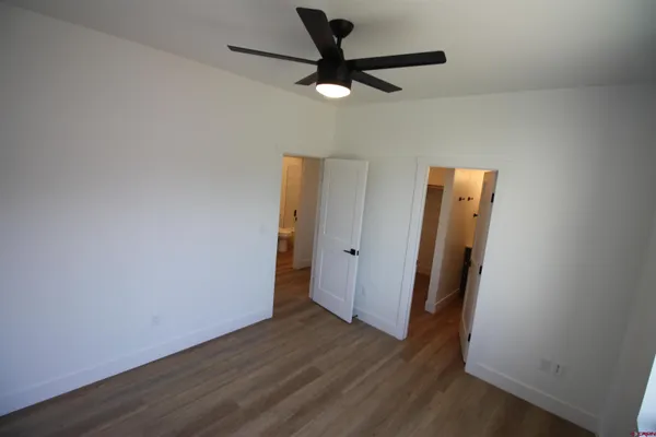 a view of a room with wooden floor and a ceiling fan