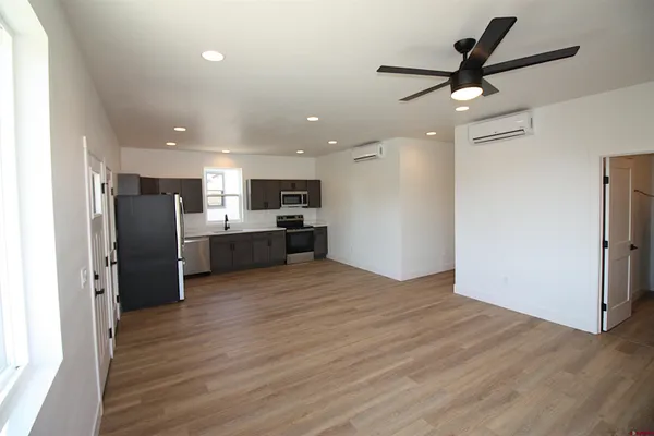 a view of kitchen with stainless steel appliances refrigerator stove and wooden floor